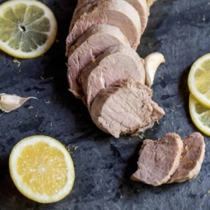 sliced pork tenderloin on table with lemon slices