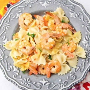 a large plate with a small serving of shrimp scampi garnished with parsley