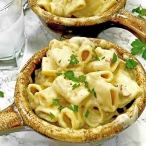 a small bowl with a serving of rigatoni mac n cheese garnished with parsley