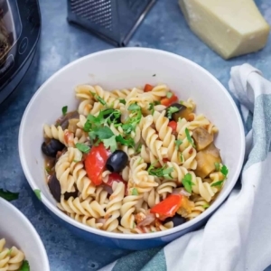 a bowl of mediterranean pasta topped with parsley