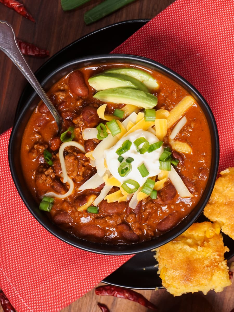 overhead shot of a bowl of chili topped with sour cream, cheese, and green onion