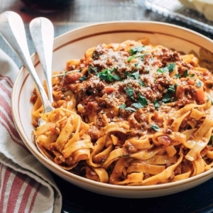 a bite of bolognese topped with parmesan and cilantro