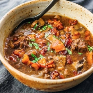 a bowl of beef bourguignon garnished with cilantro