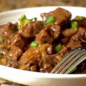 a bowl of beef stew lightly garnished with green onion