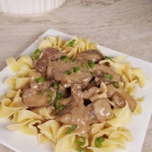 beef stroganoff garnished with scallions on a square plate