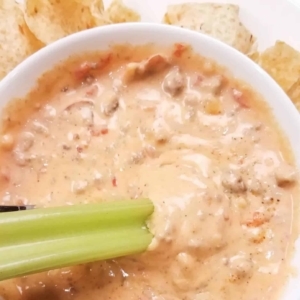 dipping celery into cheeseburger dip