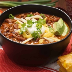 chili in a small bowl topped with sour cream, shredded cheese, and green onion