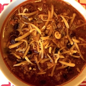 overhead view of a bowl of chili topped with shredded cheddar