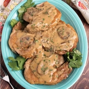 overhead shot of pork chops topped with mushroom gravy and bits of cilantro