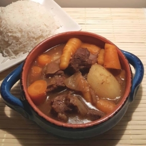 a handled bowl filled with japanese beef curry next to a plate of rice