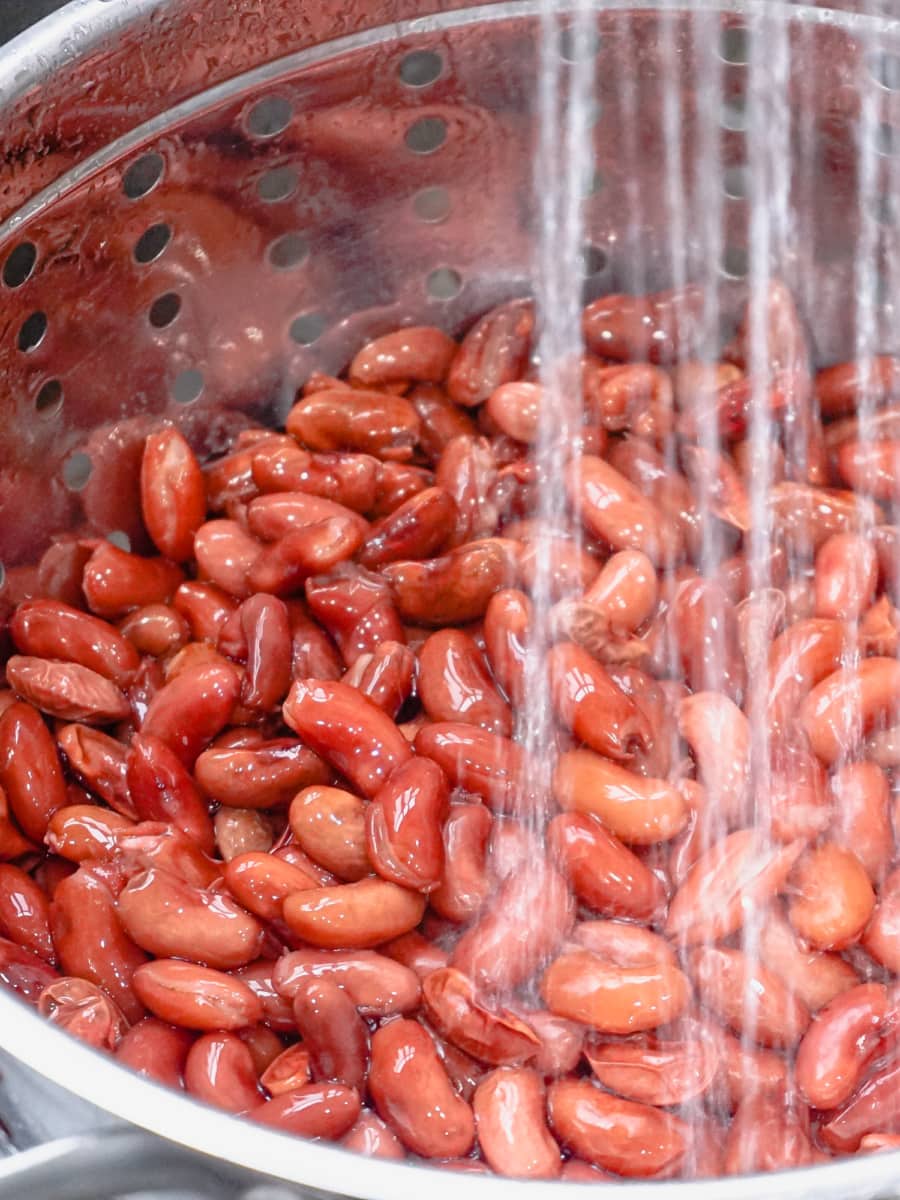 rinsing red kidney beans in a metal colander