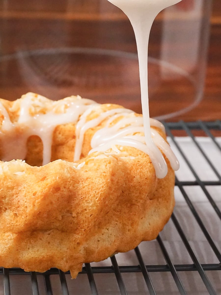 pouring a glaze over a coconut cake