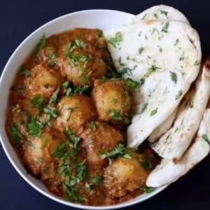 overhead shot of dum aloo in a bowl garnished with cilantro