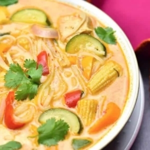 close up of thai red curry soup garnished with pieces of cilantro