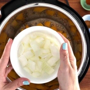 adding diced onion to butternut squash soup