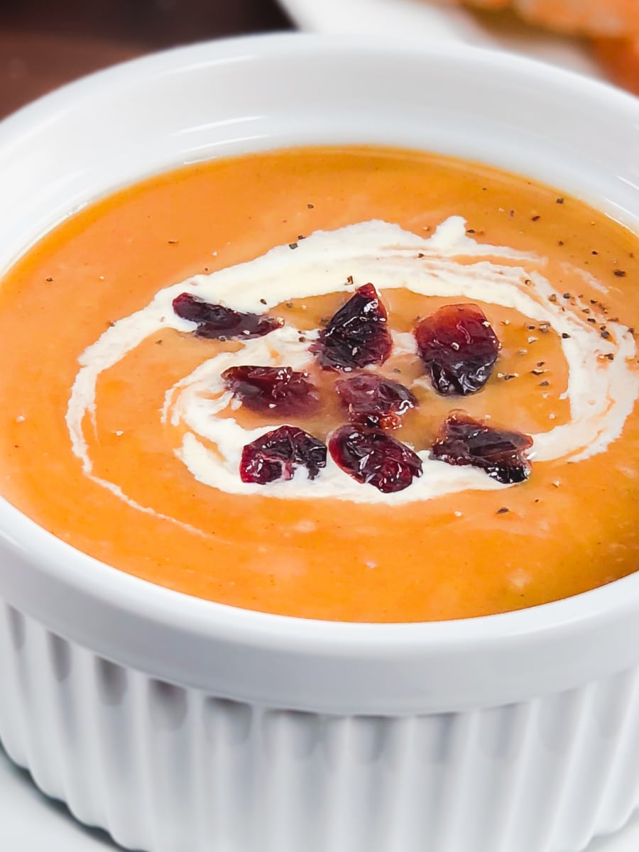 butternut squash soup in a small bowl with dried cranberries and cream