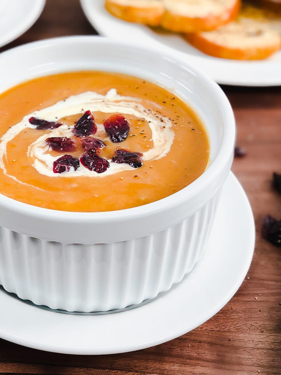 side view of butternut squash soup with cream and dried cranberries