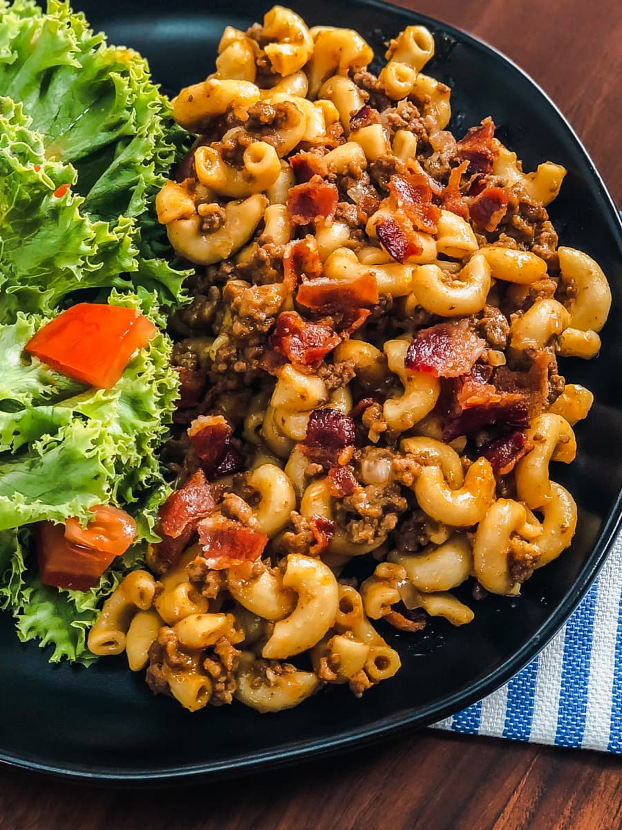 a plate of cheeseburger mac served with lettuce and tomato