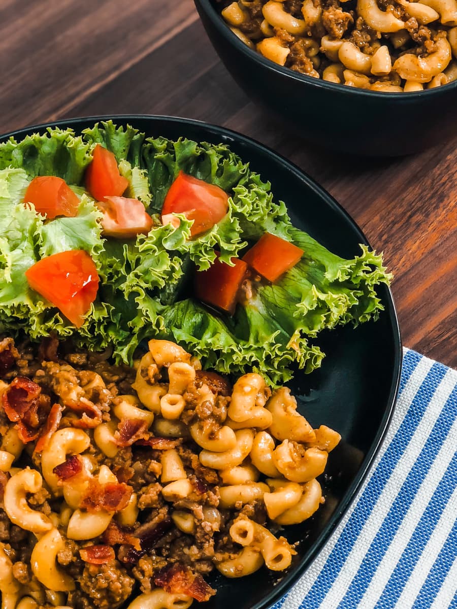 cheeseburger mac and cheese served on a plate with salad and a bowl of cheeseburger mac in the background