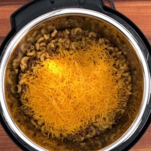 adding shredded cheese to an instant pot pasta casserole