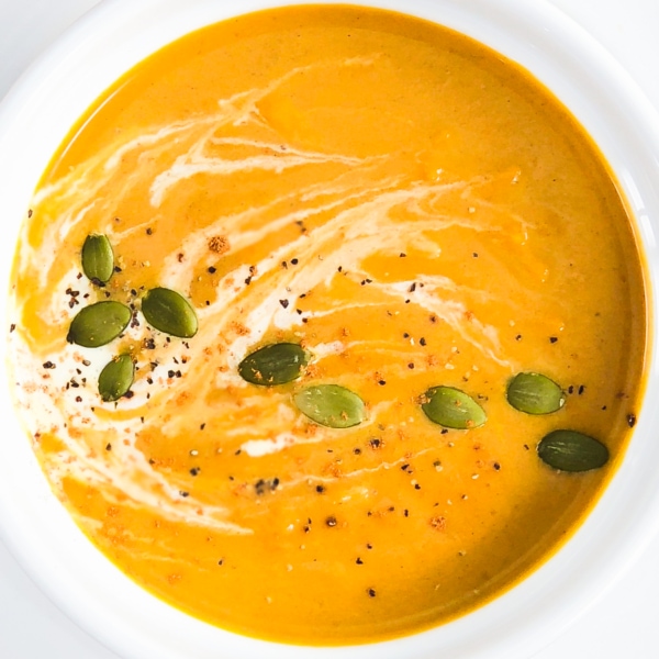 a bowl of instant pot pumpkin soup with cream and pumpkin seeds