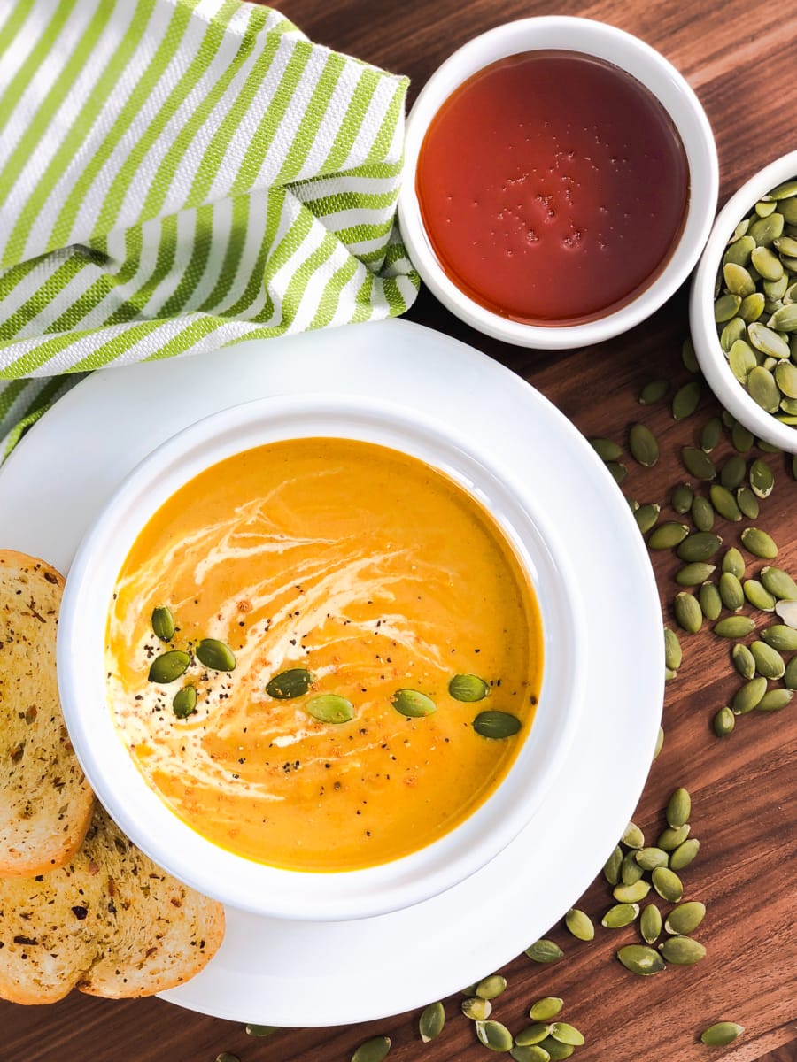 a bowl of homemade pumpkin soup served with two pieces of garlic toast