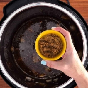 adding dark brown sugar to the pumpkin soup in the instant pot