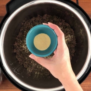 adding garlic powder to spaghetti and meat sauce in the instant pot