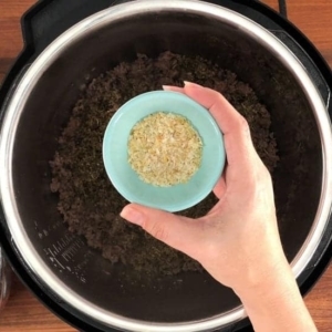 adding minced onion to spaghetti and meat sauce in the instant pot