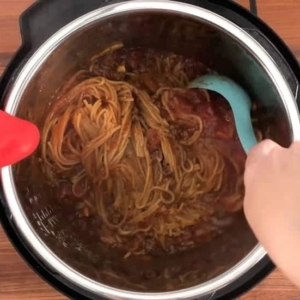 instant pot spaghetti and meat sauce being mixed together in the instant pot