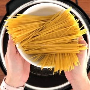 adding pasta to spaghetti and meat sauce in the instant pot