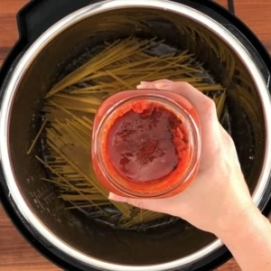 adding sauce to spaghetti and meat sauce in the instant pot