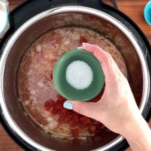 adding salt to the tomato soup