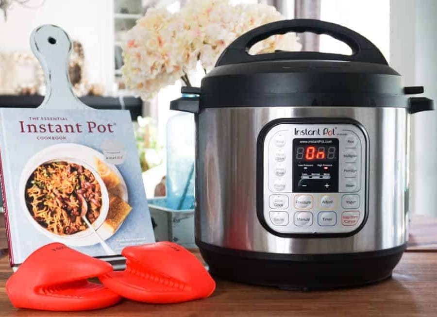 an instant pot book on a recipe holder near an instant pot and instant pot gloves