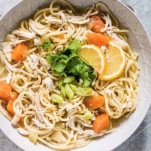 overhead shot of chicken soup in a bowl garnished with cilantro and lemon slices