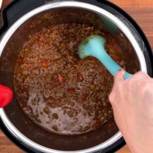 mixing the ground beef and beef broth in the instant pot