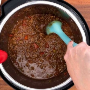 mixing the ground beef and beef broth in the instant pot