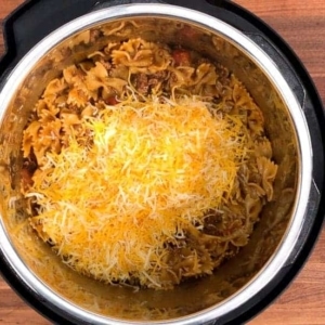 adding shredded mexican cheese to the instant pot taco pasta