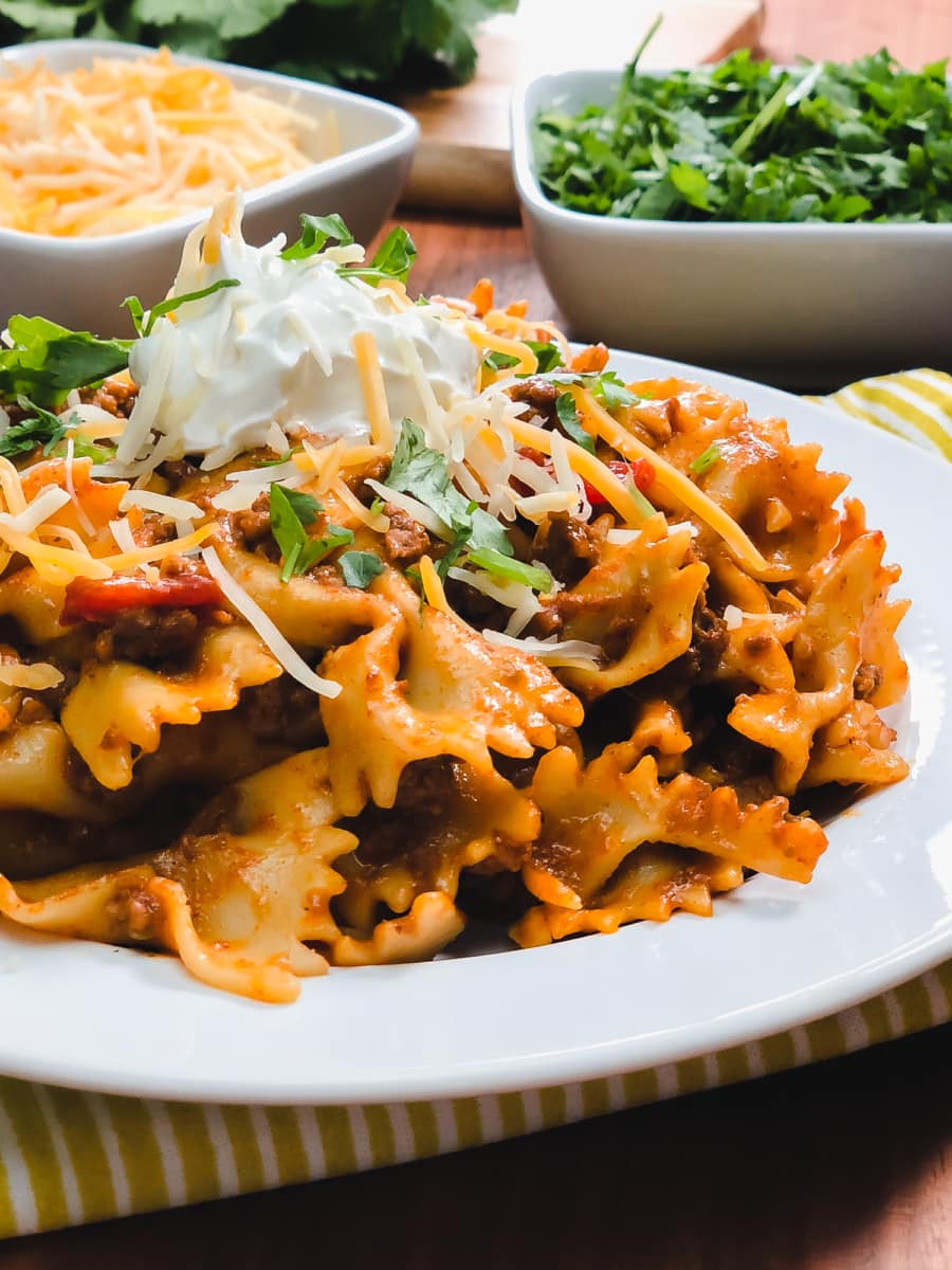 homemade taco pasta topped with cheese and sour cream and garnished with cilantro