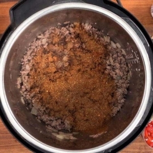 seasoning instant pot taco soup with a blend of chili, cumin and other spices