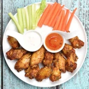 overhead shot of buffalo chicken wings with dipping sauce, celery, and carrots