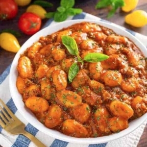 a bowl of sausage gnocchi garnished with basil