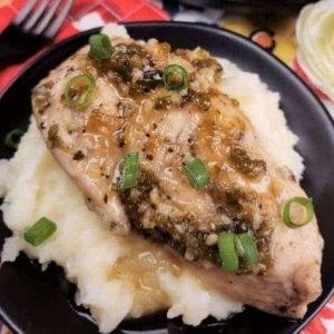 close up of jalapeno honey chicken garnished with green onion on top of mashed potatoes