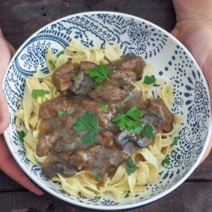 overhead shot of sirloin beef tips in mushroom gravy on pasta garnished with cilantro