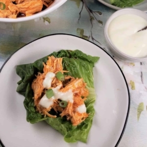 a plate of shredded buffalo chicken on a bed of lettuce