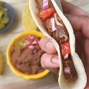 refried beans in a flour tortilla with onions and diced tomatoes