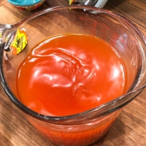 chicken broth with goya seasoning in a measuring cup