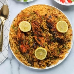 overhead shot of fish biryani topped with two slices of lemon