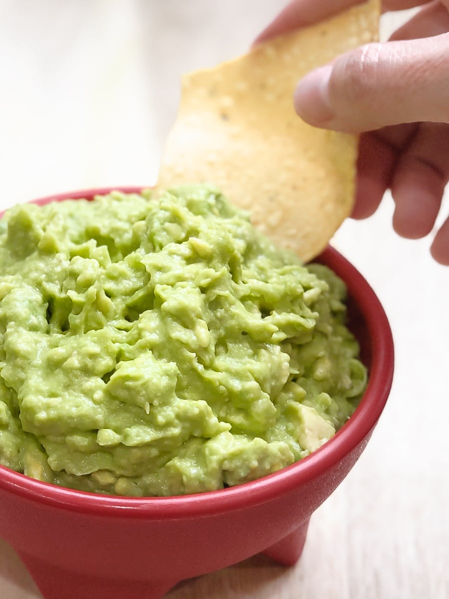 dipping a tortilla chip into fresh homemade guacamole