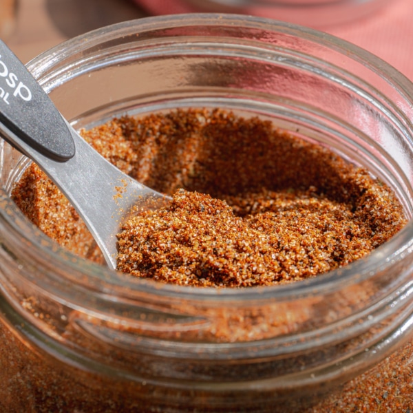 a tablespoon laying inside a glass jar with taco seasoning